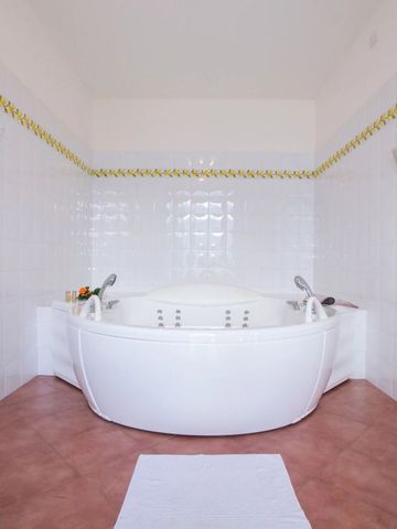 Große runde Badewanne in einem hellen Badezimmer mit weißen Kacheln und braunem Fliesenboden