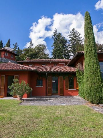 Außenansicht einer roten Villa mit grünen Bäumen und gepflegtem Rasen