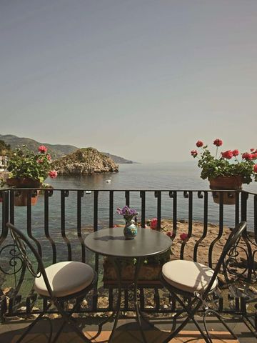 Balkon mit Sitzbereich und Blumen mit Meerblick.