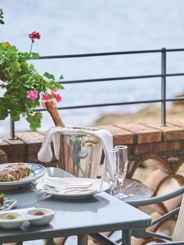 Terrasse mit Meerblick und gedecktem Tisch mit Speisen und Getränken