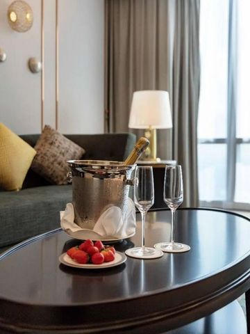 Champagnerkübel mit zwei Gläsern und Erdbeeren auf eleganter Tischplatte im Hotelzimmer.