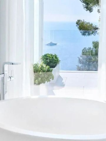 Weißes Bad mit freistehender Wanne und Panoramablick aufs Meer