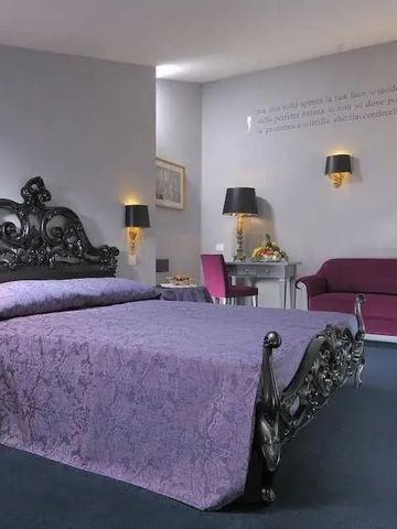 Geräumiges Hotelzimmer mit edlem, antikem Bett und lila Akzenten