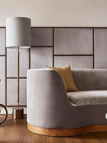 Runder Polstersessel mit goldenen Kissen vor moderner Wandverkleidung.