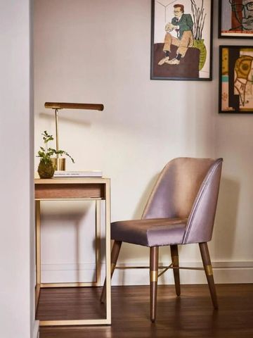 Schreibtisch mit Designstuhl und dekorativer Kunst im Hintergrund.