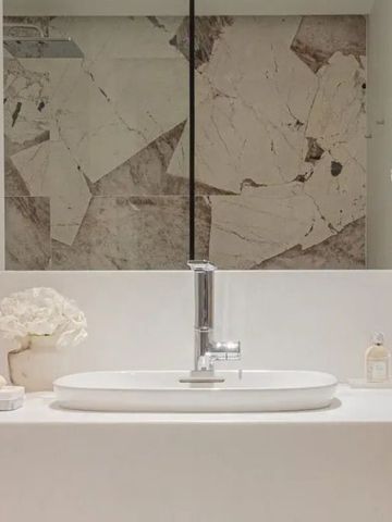 Luxuriöses Badezimmer mit weißen Armaturen und Marmorwand