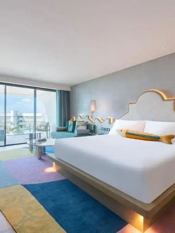 Helles Hotelzimmer mit großem Bett und Blick auf den Balkon