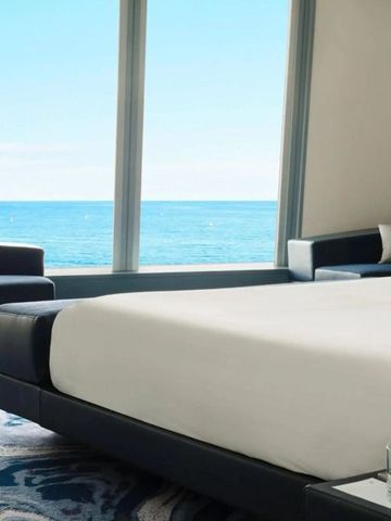 Hotelzimmer mit Meerblick und großem Bett neben bodentiefen Fenstern