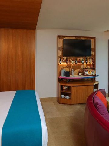 Zimmeransicht mit Bett, Balkon und großen Fensterfronten