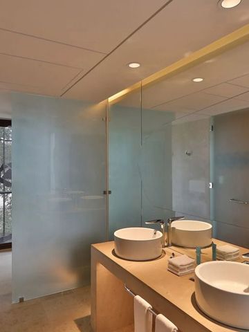 Modernes Badezimmer mit zwei Waschbecken und halbtransparenten Duschabtrennungen