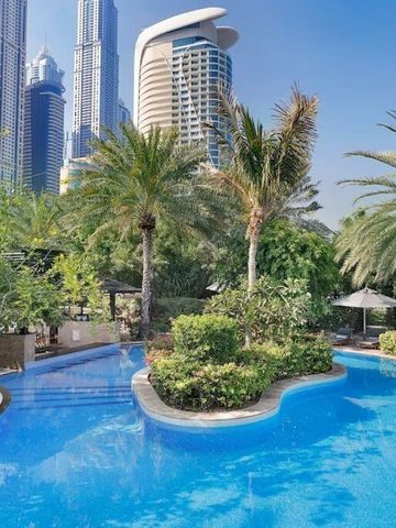 Blauer Außenpool umgeben von Palmen im W Dubai Mina Seyahi mit Blick auf moderne Gebäude