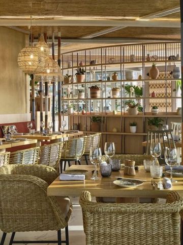 Elegantes Restaurant mit Rattanmöbeln und dekorativen Regalen im W Dubai Mina Seyahi