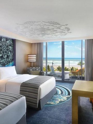 Modernes Hotelzimmer mit zwei Betten und Meerblick durch große Fenster