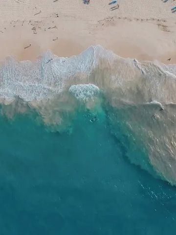 Luftaufnahme der Wellen, die an einem tropischen Sandstrand brechen