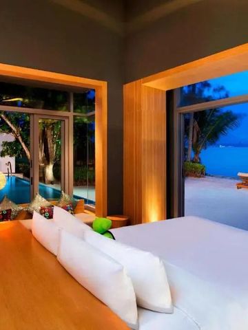 Luxus-Schlafzimmer mit Blick auf privaten Pool und Strand in der Dämmerung