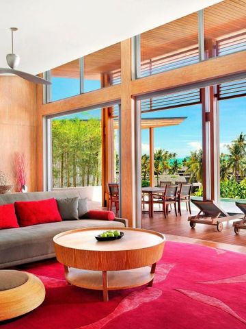 Helle Villa-Wohnzimmer mit rotem Teppich und großen Fenstern zum Garten