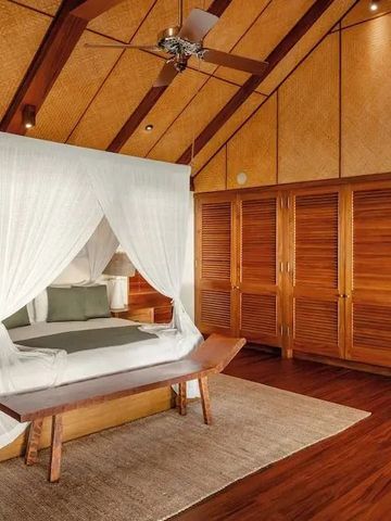 Geräumiges Schlafzimmer mit Himmelbett und Holzakzenten in tropischem Stil.