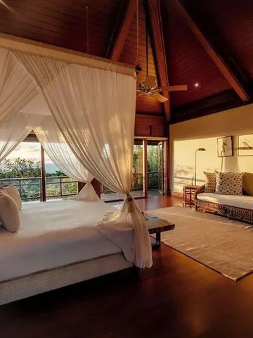 Schlafzimmer mit Himmelbett und Panoramablick bei sanftem Abendlicht.