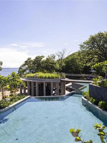 Großer Infinity-Pool mit Blick auf grüne Landschaft und Meer im Hintergrund