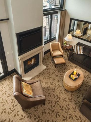 Wohnzimmer mit Kamin, Polstermöbeln und großen Fenstern mit Ausblick