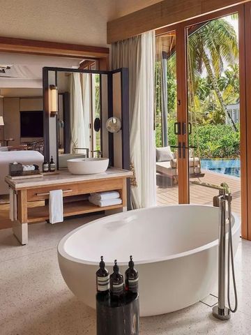 Modernes Badezimmer mit freistehender Badewanne und Blick auf den Pool