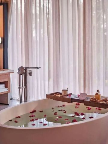 Freistehende Badewanne mit Rosenblüten in einem eleganten Badezimmer