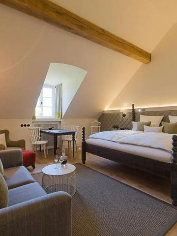 Gemütliches Dachgeschosszimmer mit Holzbalken und komfortablen Möbeln