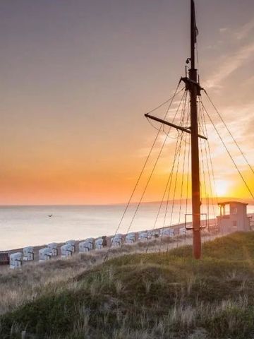 Strand in der Abenddämmerung mit Strandkörben und einem Mast