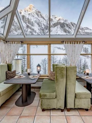 Gemütlicher Wintergarten mit Bergblick und eleganten Sitzgelegenheiten