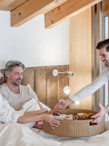 Frühstück im Bett Moment mit lächelndem Paar und Hotelpersonal