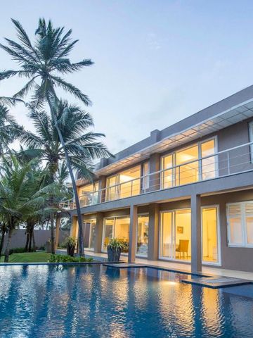 Modernes Hotelgebäude mit beleuchtetem Pool und Palmen im Vordergrund