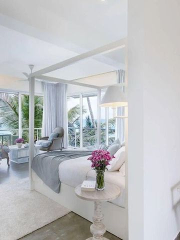 Helles Schlafzimmer mit Himmelbett und großen Fenstern mit Meerblick