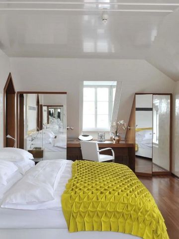 Helles Schlafzimmer mit Dachschräge und gelber Tagesdecke