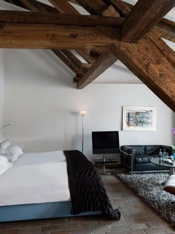 Modernes Loft-Zimmer mit freiliegenden Holzbalken und gemütlicher Sitzecke im Widder Hotel
