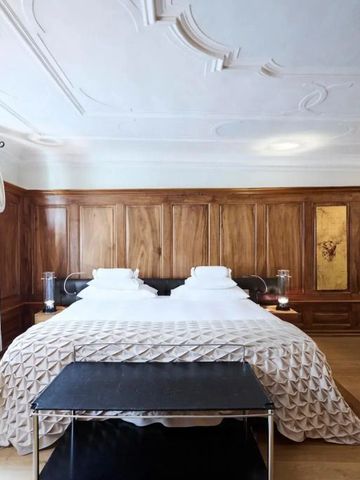 Luxuriös eingerichtetes Zimmer mit Holzwänden und weißer Bettwäsche