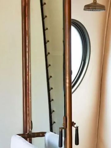 Stilvolles Badezimmer mit Holz- und Metallelementen und rundem Fenster.