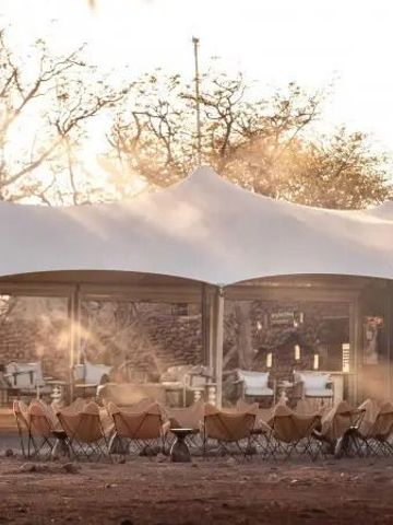 Outdoor-Lounge mit weißen Zeltdächern und gemütlichen Sitzbereichen bei Sonnenuntergang