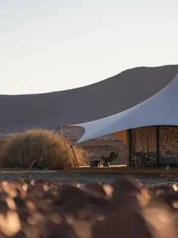 Luxuszelt vor karger Wüstenlandschaft bei Sonnenuntergang