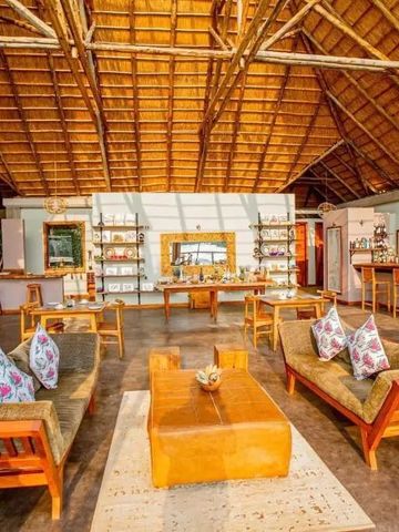 Geräumige Lounge mit Holzmöbeln und Strohdach im Lodge-Stil