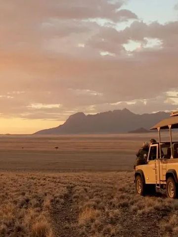 Offenes Fahrzeug in der Savanne mit Bergpanorama bei Sonnenuntergang