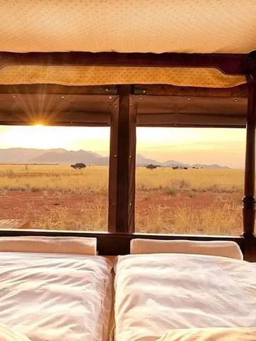 Blick vom Bett auf die offene Savanne bei Sonnenuntergang im Wolwedans Boulders Camp.