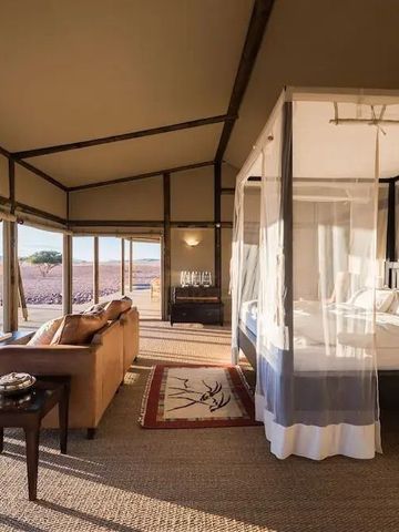 Großzügiges Zimmer mit Himmelbett und Panoramafenstern im Wolwedans Boulders Camp.