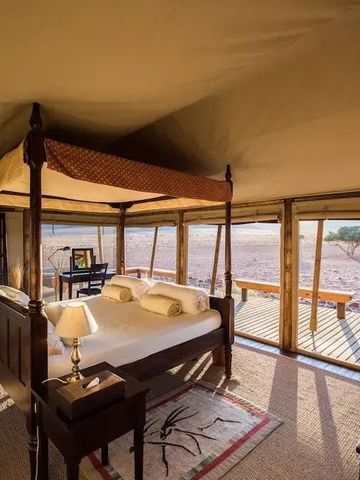 Komfortables Schlafzimmer mit Himmelbett und Wüstenblick im Wolwedans Boulders Camp.
