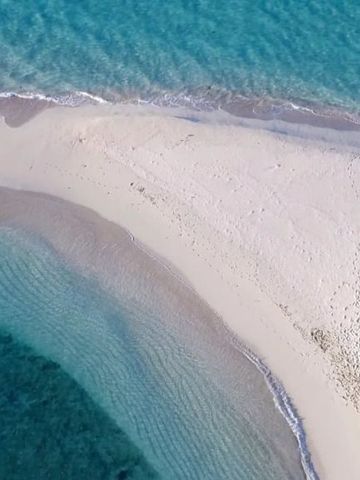 Luftaufnahme einer schmalen sandigen Landzunge im klaren Ozean.