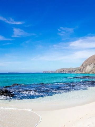 Klarer Ozean mit felsiger Küste und blauem Himmel.