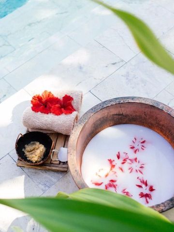 Entspannendes Bad mit Blumenblättern und Handtüchern am Pool.