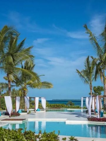 Poollandschaft mit Palmen und Liegen unter blauem Himmel