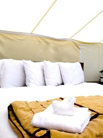 Gemütliches Bett in einem komfortablen Zeltzimmer mit gefalteten Handtüchern