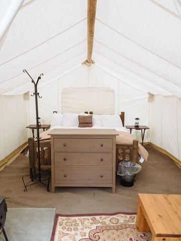 Zeltunterkunft mit einem Holzbett und stilvollen Möbeln