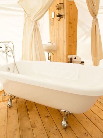 Freistehende Badewanne im Zelt-Badezimmer mit Holzfußboden und Vorhängen